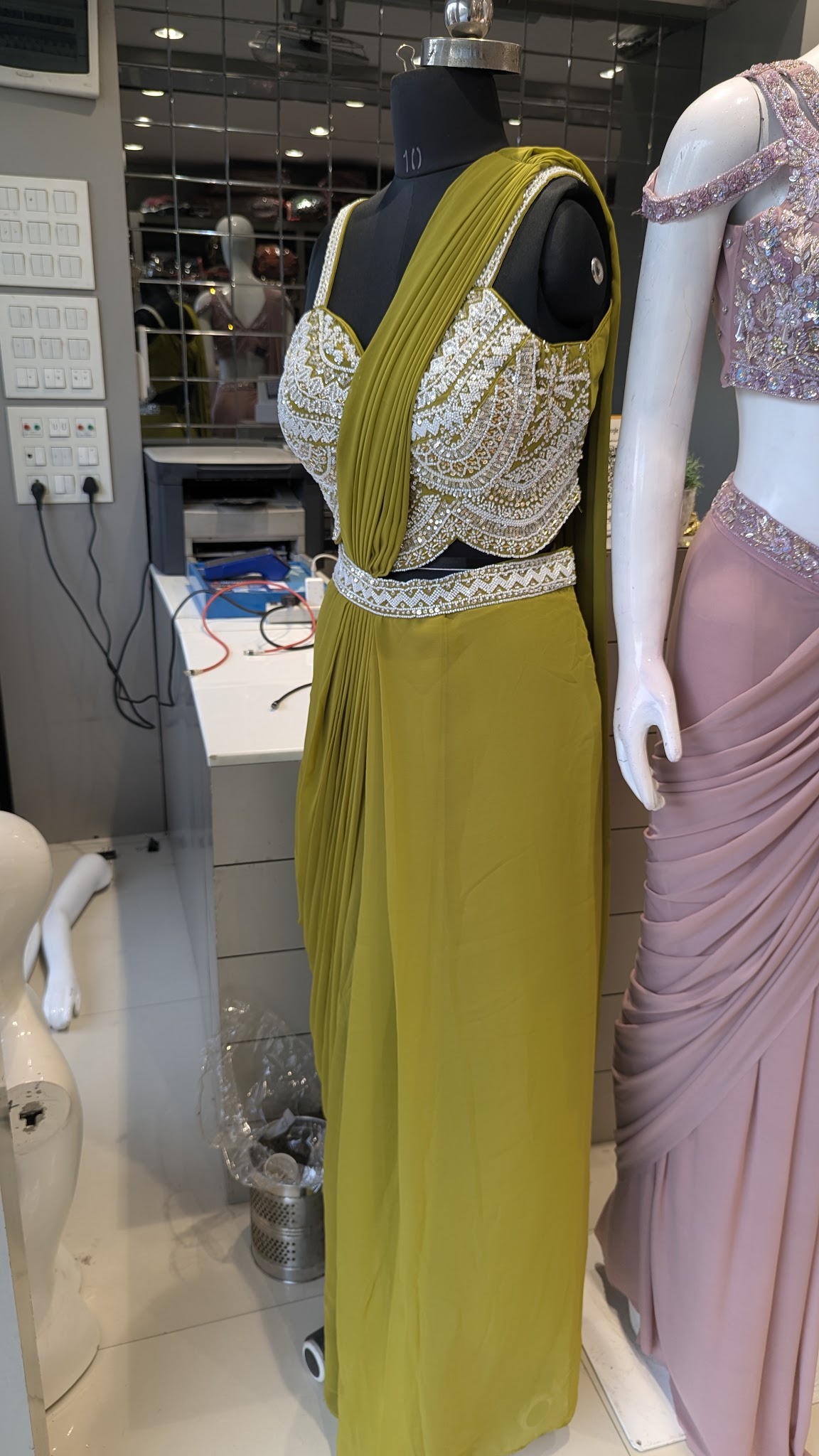 An embellished yellow-green lehenga with an embroidered blouse on display.